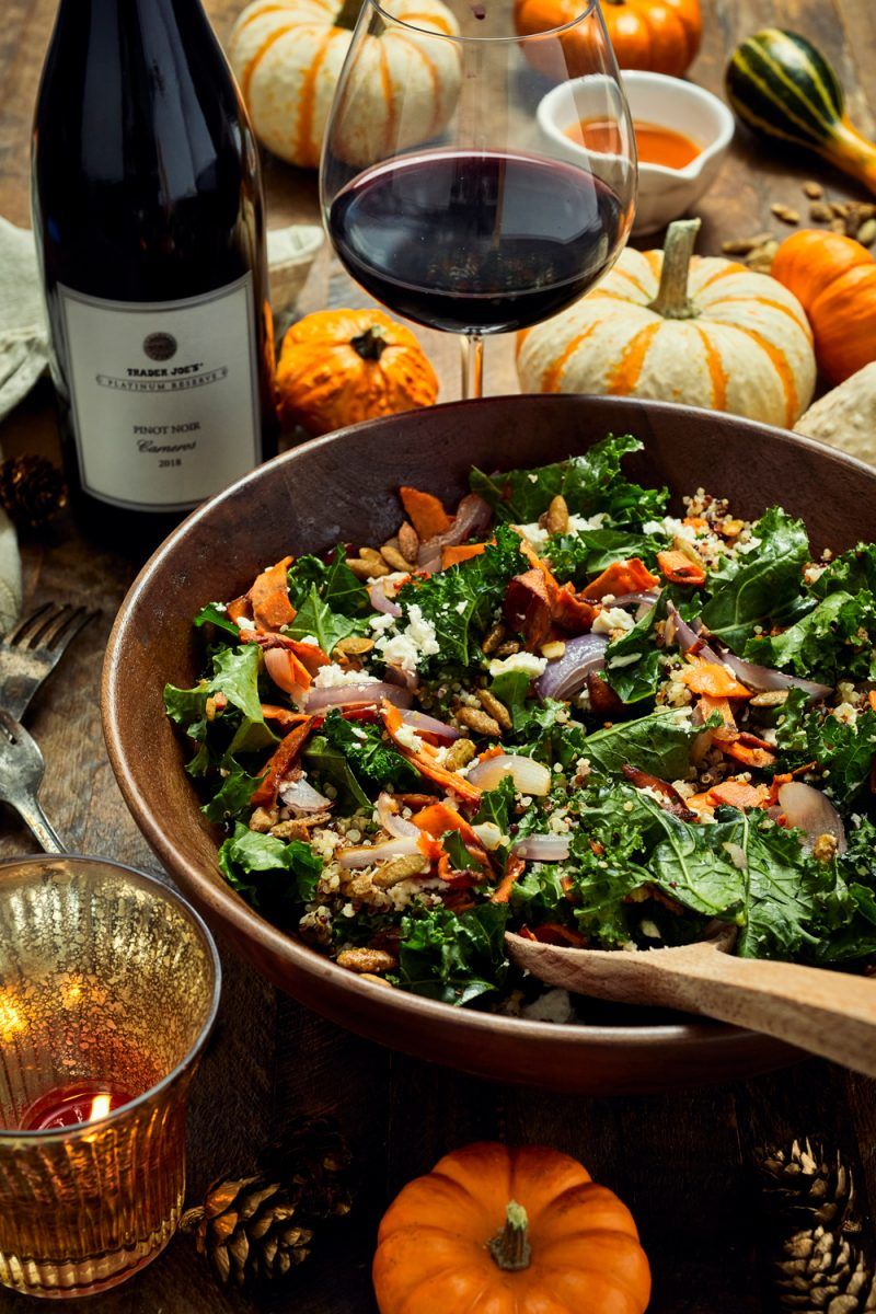 Trader Joe's Warm Sweet Potato Salad Bowl Recipe | Trader Joe's Wine by popular D.C. lifestyle blogger, Alicia Tenise: image of a bottle of Trader Joe's Pinot Noir, a half filled wine lass, mini pumpkins and a wooden bowl filled with warm sweet potato salad.
