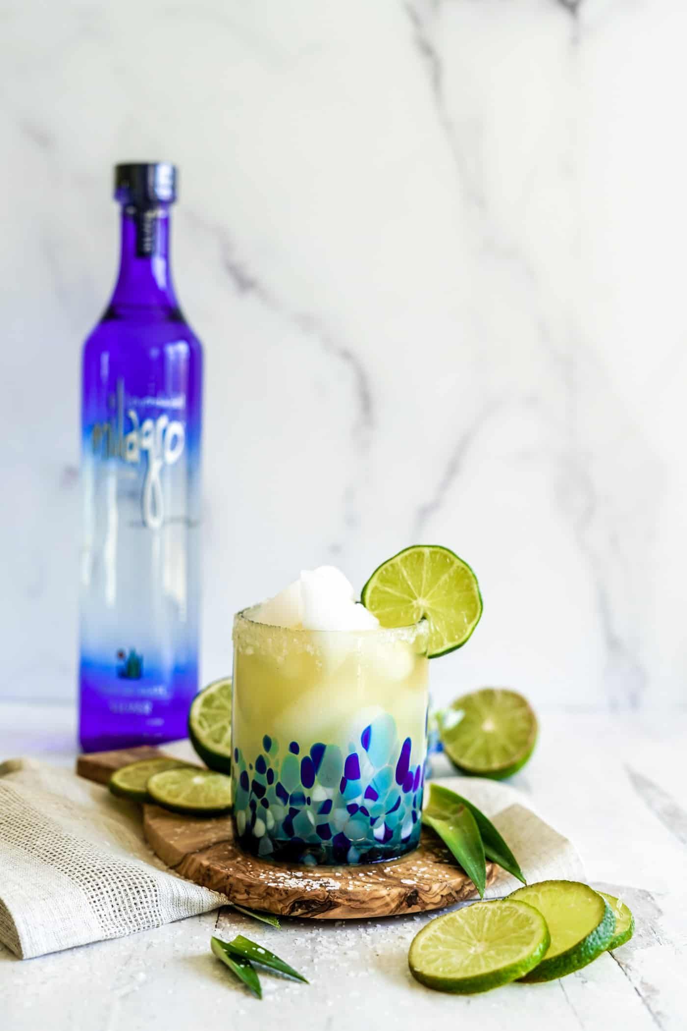 A single margarita glass filled with a Cadillac Margarita with a lime wedge