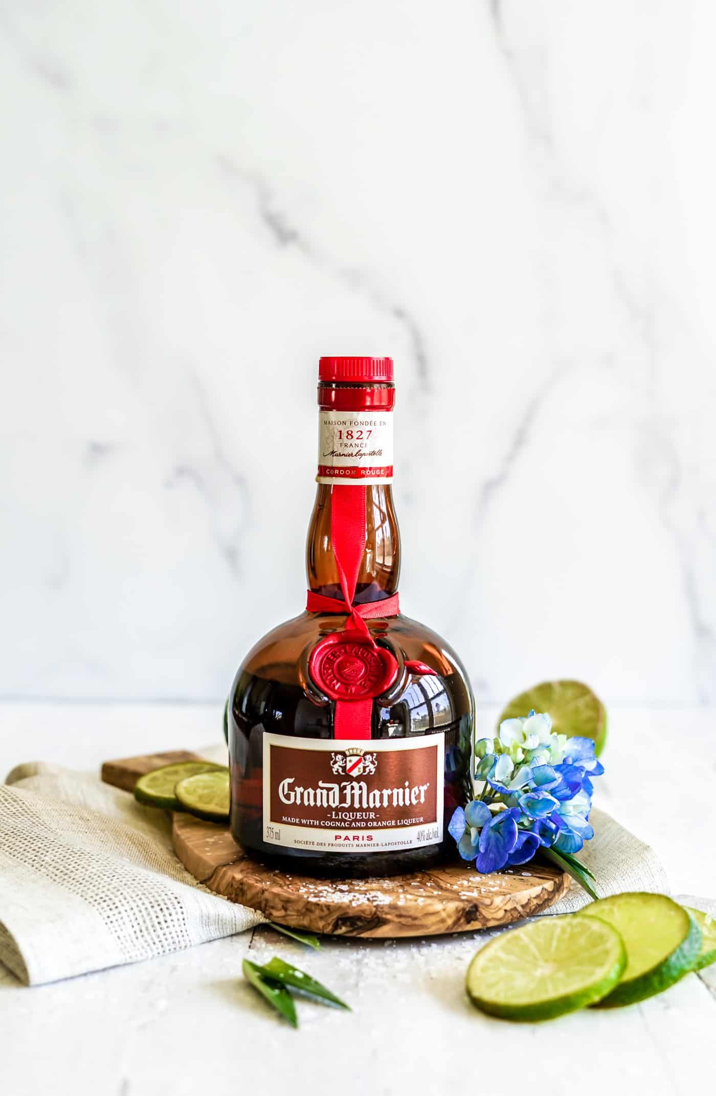 A bottle of Grand Marnier, flowers and lime wedges