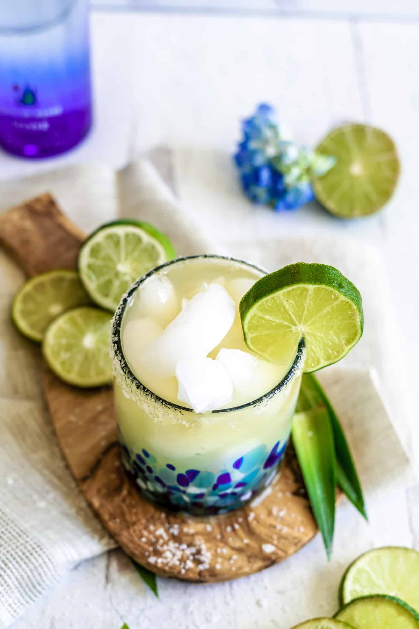 A single margarita glass filled with a Cadillac Margarita with a lime wedge