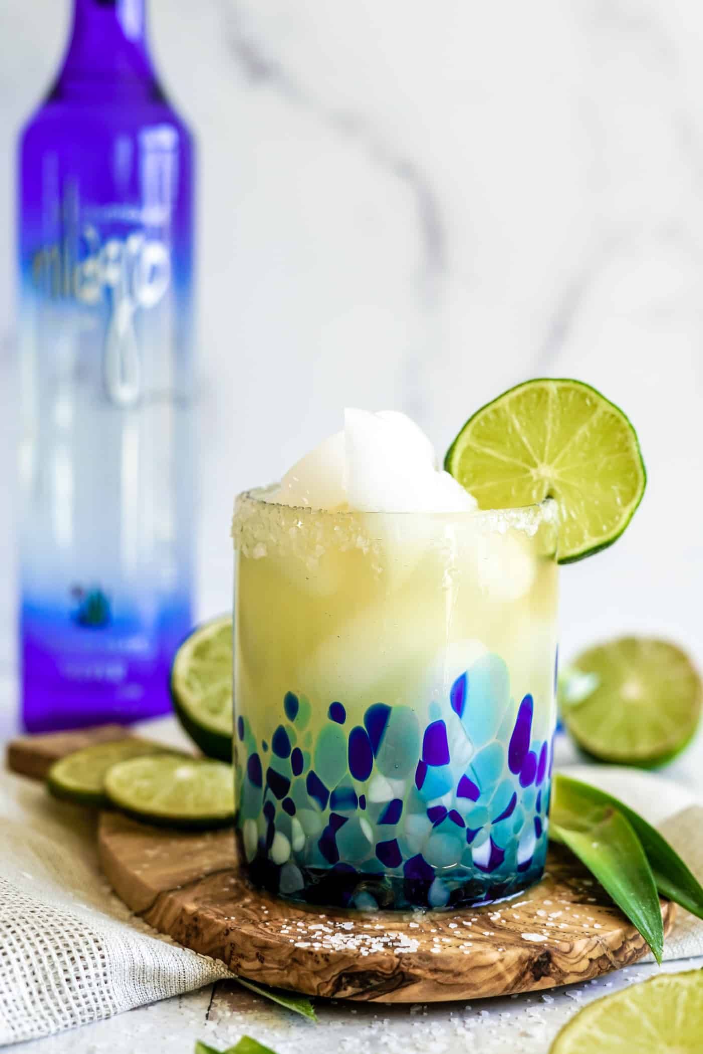 A single margarita glass filled with a Cadillac Margarita with a lime wedge