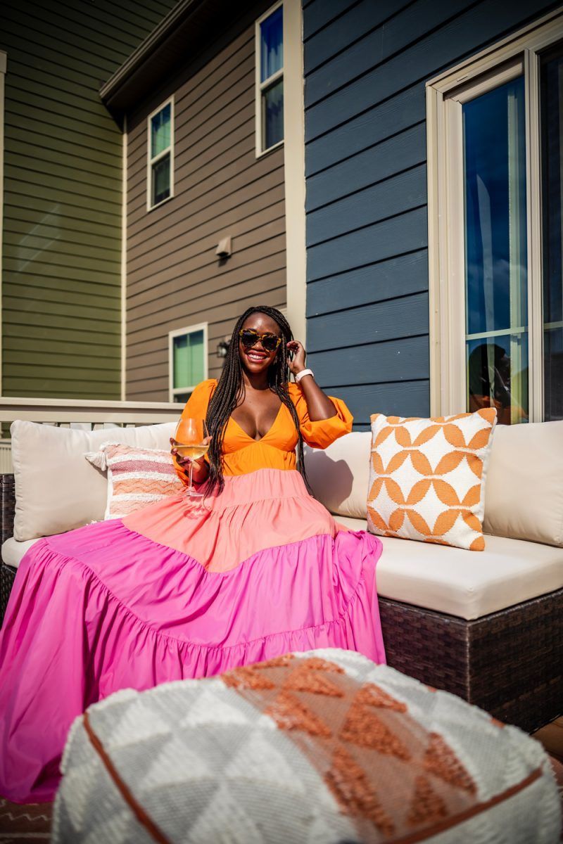 Colorblock Dress for Spring | Social Distancing Mindset by popular D.C. lifestyle blogger, Alicia Tenise: image of a woman sitting outside on her deck next to a Target Royal Stripe Outdoor Rug and wearing a Neiman Marcus Staud Meadow Colorblock Dress and Revolve Karen Walker Number One sunglasses.