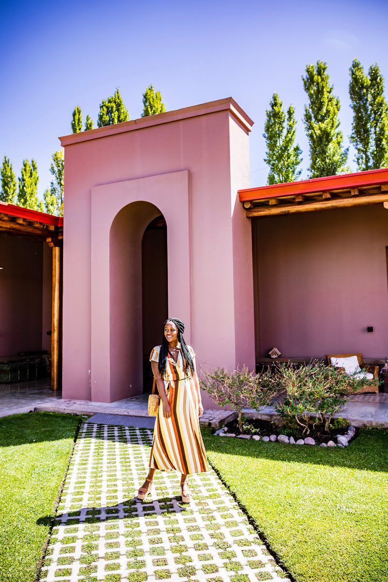 Tom's Travel Photography Tips: How to Nail the Perfect Shot While Traveling by popular travel blogger, Alicia Tenise: image of a woman standing in front of a pink building.