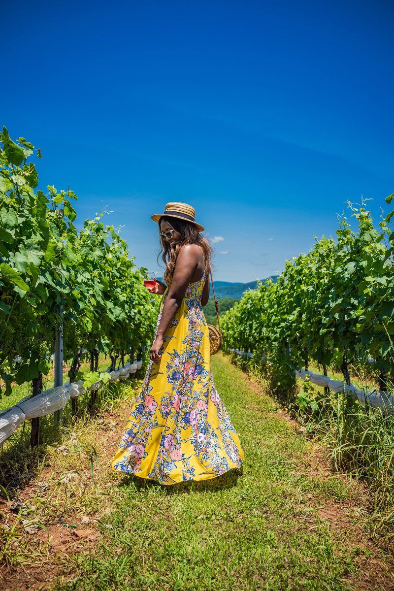 Free People Through The Vine Maxi Dress - I'm Moving To Charlottesville, VA by popular DC style blogger, Alicia Tenise | Tom's Travel Photography Tips: How to Nail the Perfect Shot While Traveling by popular travel blogger, Alicia Tenise: image of a woman standing in a vineyard and holding a glass of wine.