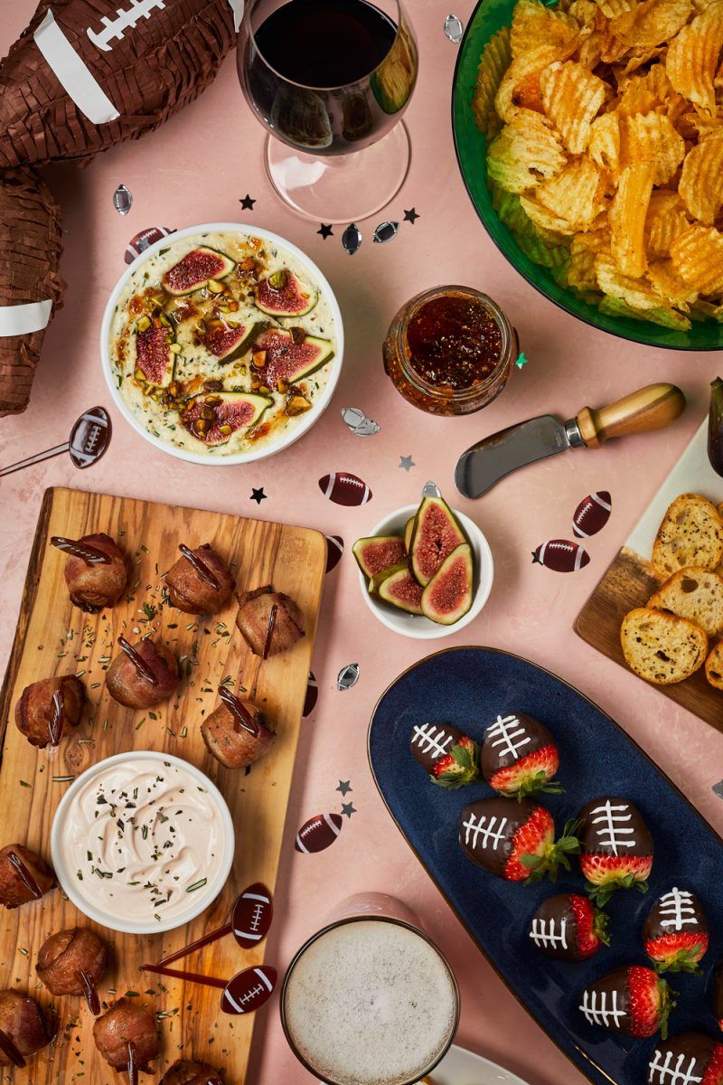 Football Party Ideas by popular D.C. lifestyle blogger, Alicia Tenise: image of chocolate covered strawberries, bowl of potato chips, glass of red wine, sliced figs, crostini bread slices, and bacon wrapped potato bites.