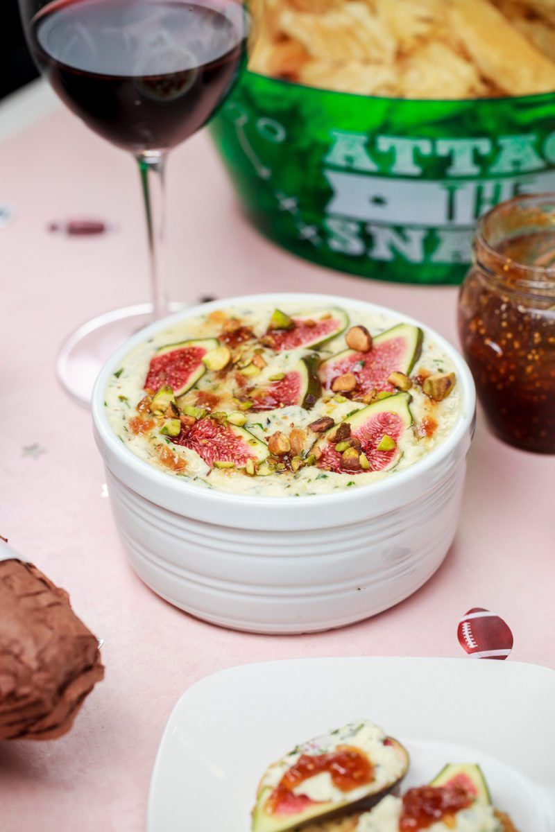 Baked Ricotta Dip with Figs and Pistachios |Football Party Ideas by popular D.C. lifestyle blogger, Alicia Tenise: image of baked ricotta and figs next to a red glass of wine.