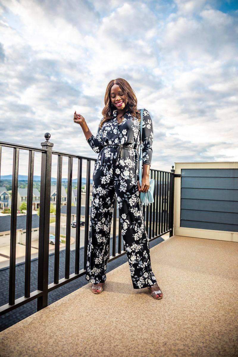 Black Floral Jumpsuit from Walmart | Summer to Fall Looks: Two Transitional Outfit Ideas Under $100 by popular Washington D.C. fashion blogger, Alicia Tenise: image of a woman standing outside and wearing a Walmart Calvin Klein Three-Quarter Floral Tie Waist Jumpsuit and Metallic Sky Circle Crossbody.