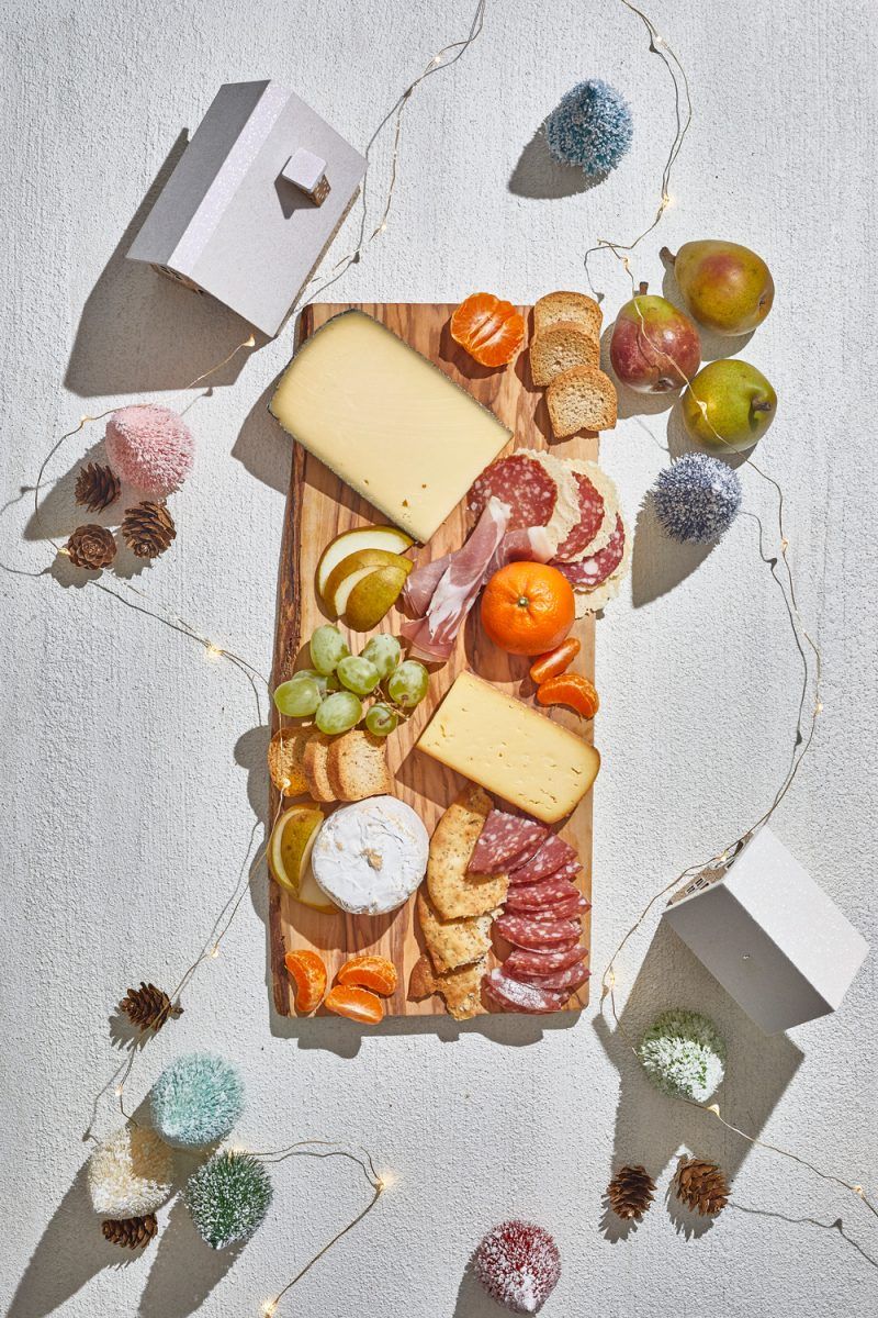 Charcuterie Board by popular D.C. lifestyle blogger, Alicia Tenise: image of a holiday Charcuterie board filled with specialty meats,crackers, cheese, fruit, and fresh rosemary sprigs.