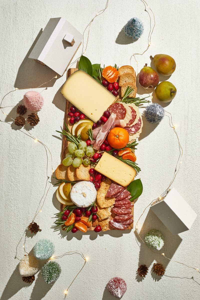 Holiday Cheese and Charcuterie Board |Charcuterie Board by popular D.C. lifestyle blogger, Alicia Tenise: image of a holiday Charcuterie board filled with specialty meats,crackers, cheese, fruit, and fresh rosemary sprigs.