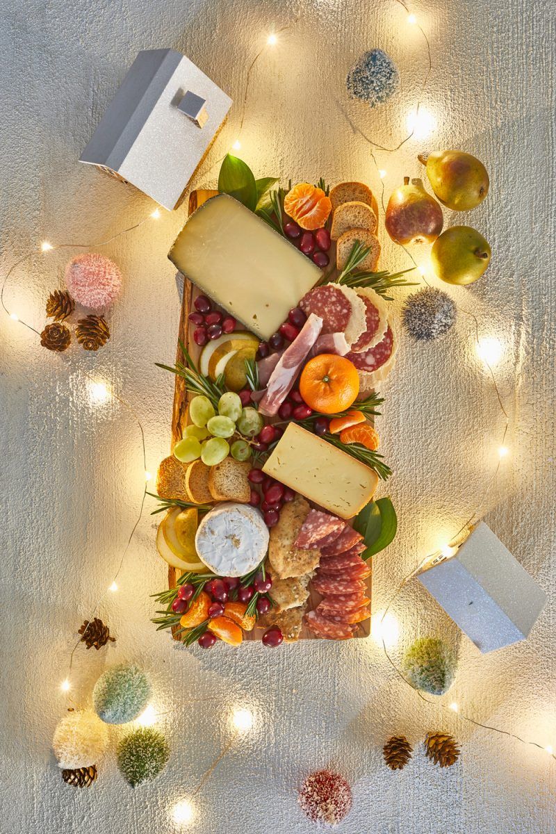 Charcuterie Board by popular D.C. lifestyle blogger, Alicia Tenise: image of a holiday Charcuterie board filled with specialty meats,crackers, cheese, fruit, and fresh rosemary sprigs.
