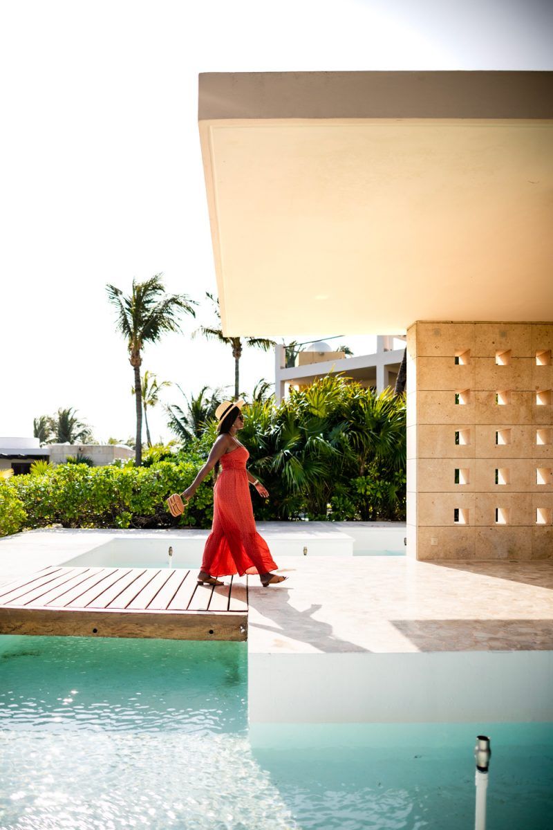 Excellence Playa Mujeres | How to Deal with Stress and Anxiety by popular DC lifestyle blogger, Alicia Tenise: image of a woman walking outside and wearing a ShopBop Free People Free People Little Of Your Love Jumpsuit, Nordstrom Brixton Joanna Straw Hat, ShopBop Karen Walker The Number One Sunglasses, and holding a Moda Operandi Cult Gaia bag.