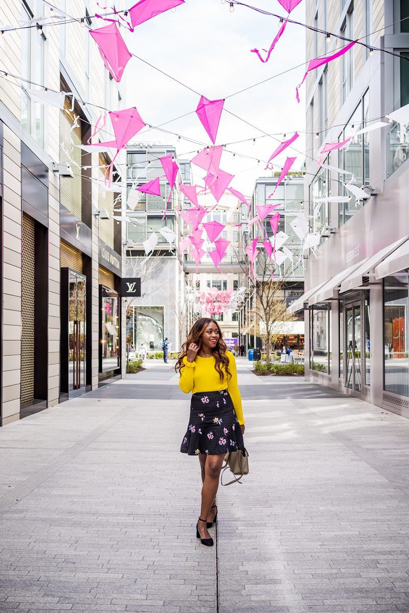 Best Things to Do in D.C. in the Spring featured by top DC blogger Alicia Tenise; Image of a woman wearing a yellow sweater and floral skirt.
