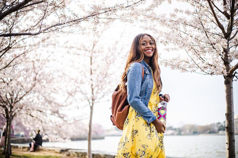 Best Things to Do in D.C. in the Spring featured by top DC blogger Alicia Tenise; Image of a woman wearing a yellow floral dress and denim jacket.