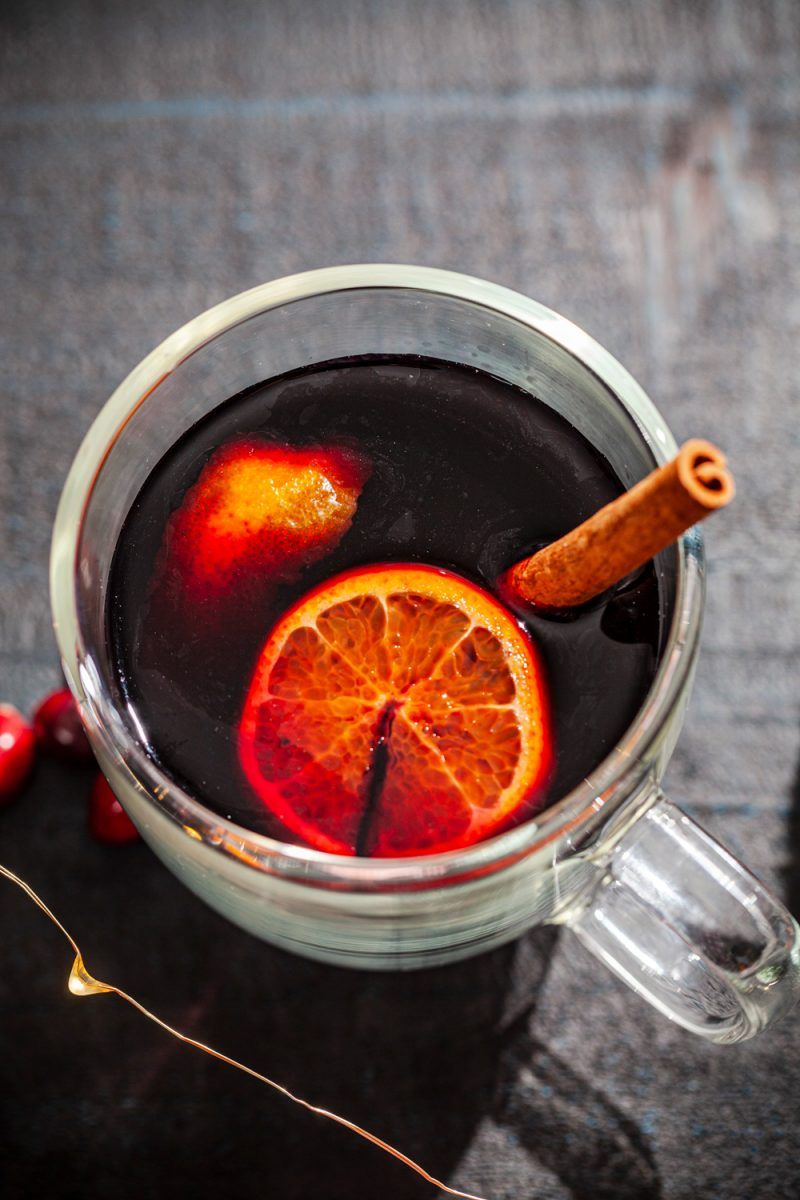 Mulled Wine Recipes by popular D.C. lifestyle blogger, Alicia Tenise: image of mulled wine in a clear mug with oranges slices and cinnamon sticks.